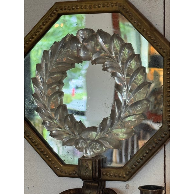 Pair of two light mirrored wall sconces, each with an octagonal beaded brass frame enclosing a mirror plate mounted with a...