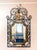 Exquisite LaBarge wrought‑iron wall mirror with scrolling frame, gilt foliate accents, and an urn‑and‑leaf crest, offering...