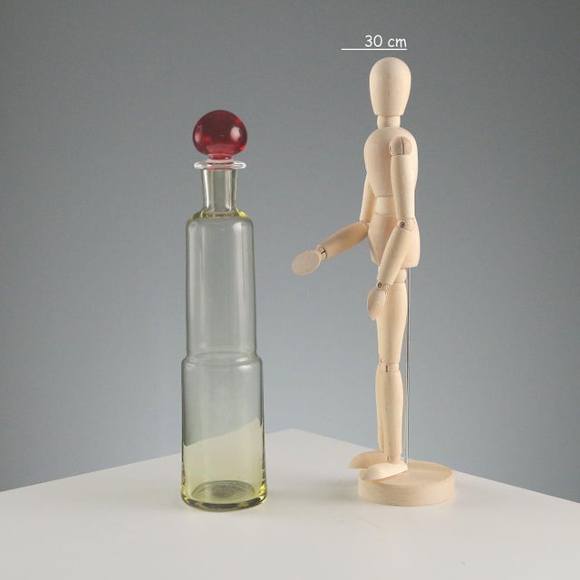 Blown glass bottle with red cap. Designer's signature and manufacturer's sticker. Bottle height 29.5 cm. Original box....