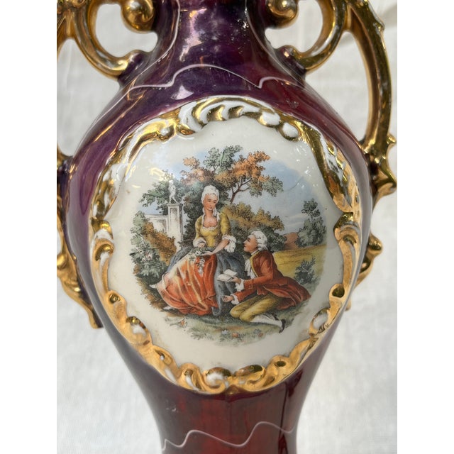 Showcasing a deep burgundy/maroon glazed porcelain body, ornate dual gold handles, and an oval central cameo medallion...
