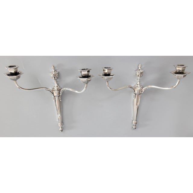 A lovely vintage pair of English Neoclassical style silver plate two arm candle sconces, circa 1950. No maker's mark....