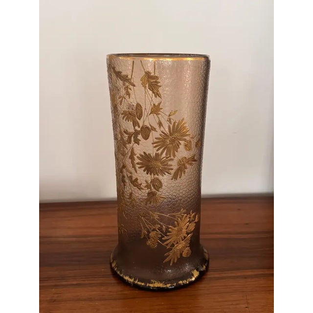 Cylindrical vase in smoked topaz glass with a fine martelé texture, richly hand-gilded with trailing daisies and foliage....