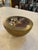 A poetic mid-century decorative bowl featuring a solid brass body topped with a clear lucite panel encasing delicate dried...