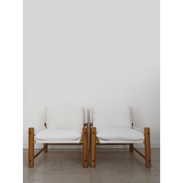 Pair of Italian armchairs with a light wood frame and removable cushions covered in ivory canvas fabric that rest on a...