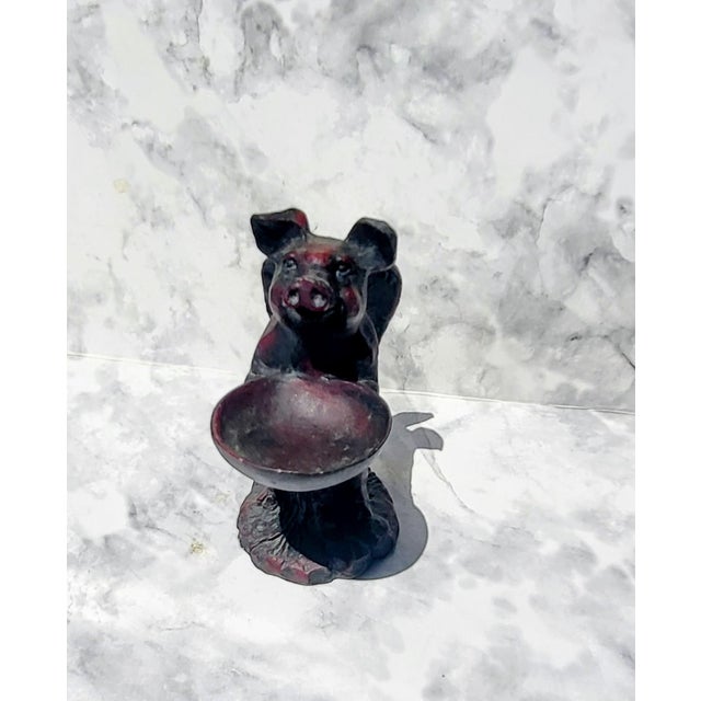 Japanese netsuke carved out of wood with a reddish stained finish. This pig has wings and is holding a serving bowl. It...
