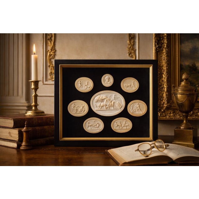 refined collection of Grand Tour–style plaster intaglios, beautifully arranged in a shadow box frame against a rich dark...