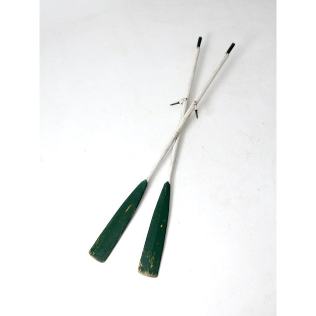 This is a pair of vintage painted wood oars. Naturally aged, forest green and white paint color the long woodem oars...
