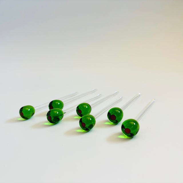 A set of 7 vintage blown art glass drink stirrers. Each made with a green and red olive on top. Each measures 4.75"L x .5"...