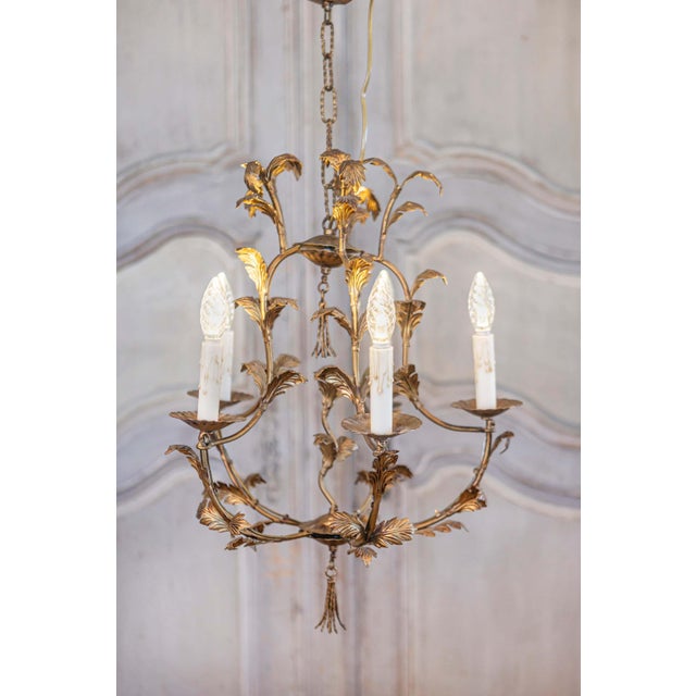 A French gilt metal five-light chandelier from the 20th century inspired by Maison Charles. This elegant French gilt metal...
