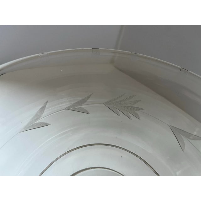 A vintage clear glass pedestal compote featuring an elegant etched laurel leaf motif encircling the bowl. The gently...