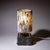 Small table lamp on a black marble base with brass fittings and a cylindrical glass shade composed of differently colored...