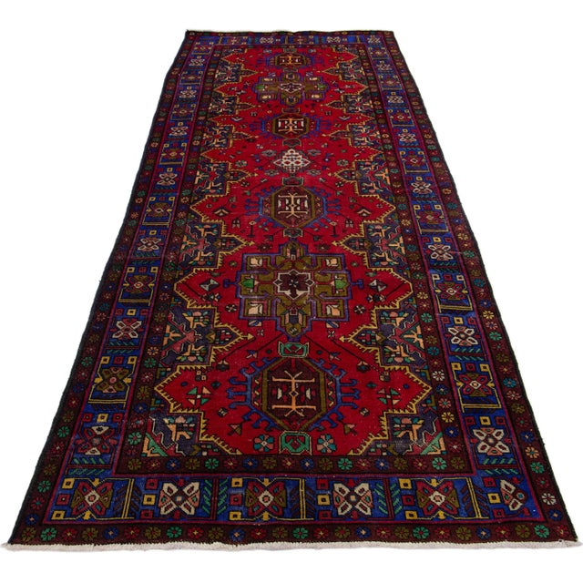 This handmade wool Persian rug has a red field with multicolor accents all over tribal design. This rug measures 5' x 13'1".