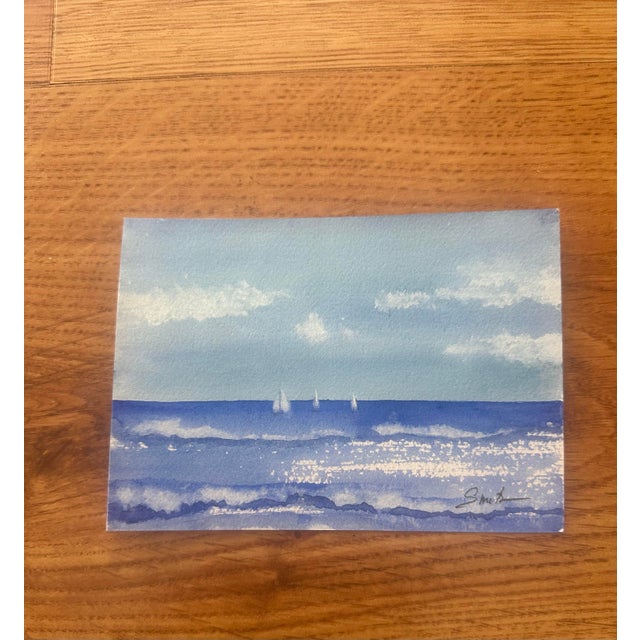 Original watercolor seascape featuring gentle ocean waves and distant sailboats beneath an expansive blue sky. Light,...