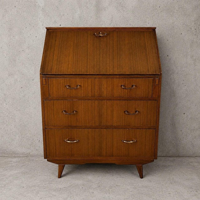 Details * Maker: Sutcliffe of Todmorden * Origin: United Kingdom * Era: 1960s * Material: Walnut veneer * Form: Fall-front...