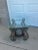 Striking architectural pair side tables featuring an ornate hand-forged style iron base with dramatic scrollwork and a...