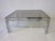 A chromed 1970's framed coffee table with a medium smoked glass top having dual frame support design details in the manner...