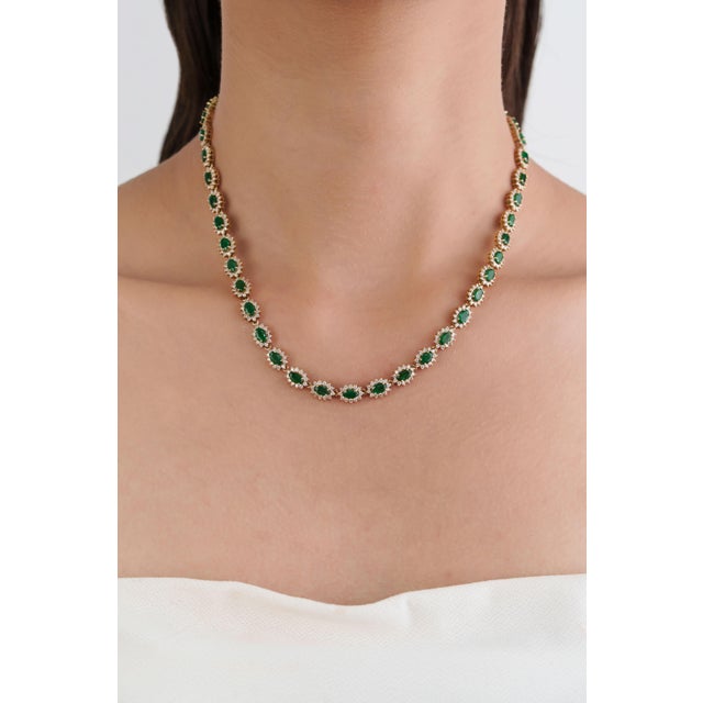 This vintage-style tennis necklace showcases 9.88 carats of natural oval emeralds, set in 14K yellow gold,each measuring...