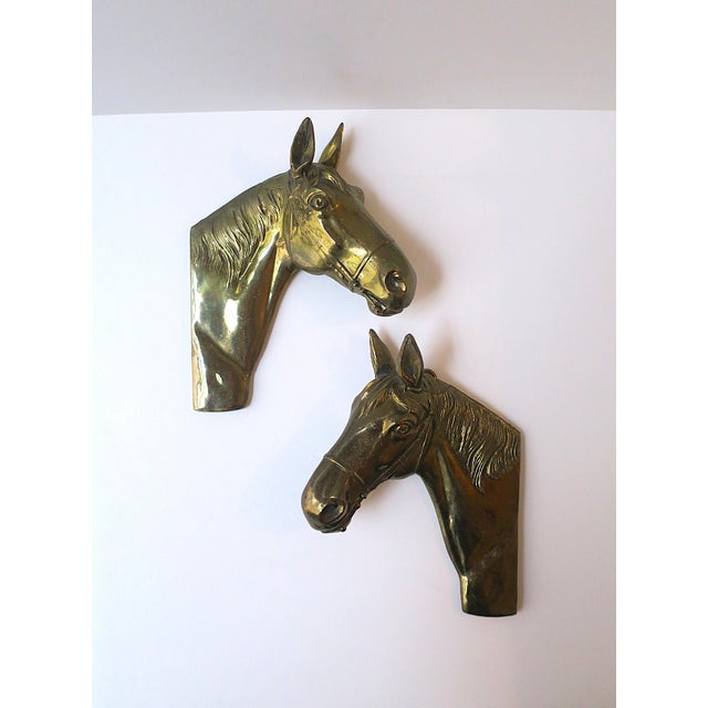 A detailed pair of brass-plated metal horse heads or busts wall art sculptures, Equestrian aesthetic, circa mid-20th...