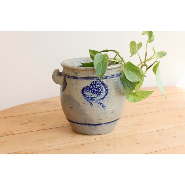 Beautiful antique Alsatian pottery jar, decorated with a traditional blue design and two rustic handles. Its textured...