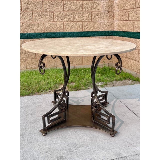 A striking neoclassical style dining table or center / foyer table in hand-worked solid steel with four scroll supports,...