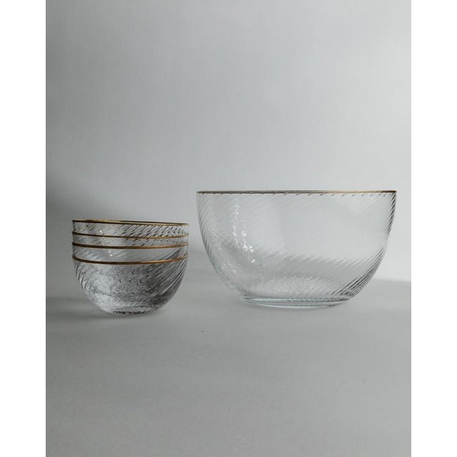 This vintage glass bowl set from the 1970s features a large salad bowl with four matching small bowls, all crafted from...