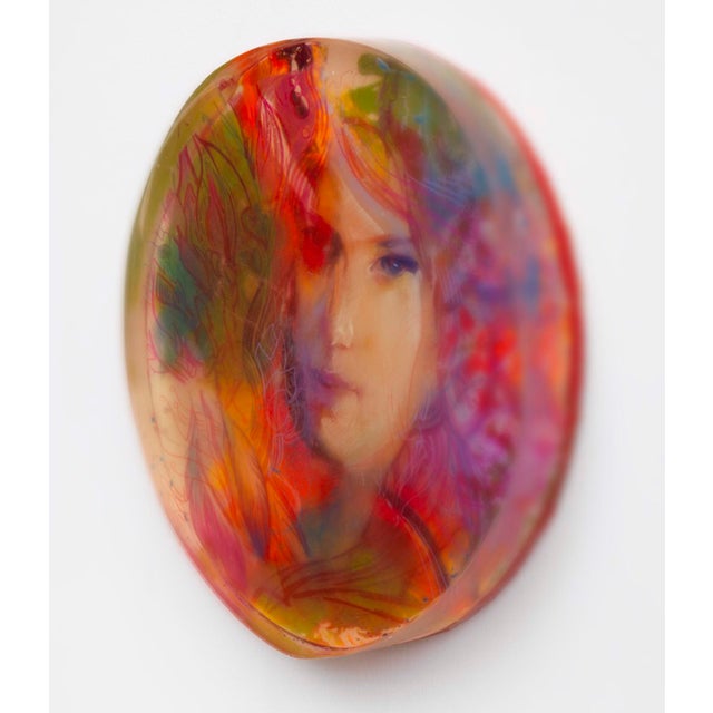 This artwork features a striking portrait that emerges from a vibrant, layered composition of colors and textures. The...