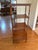 A tall four-tier wooden étagère featuring turned bobbin supports, square shelves, and a base cabinet with two small...
