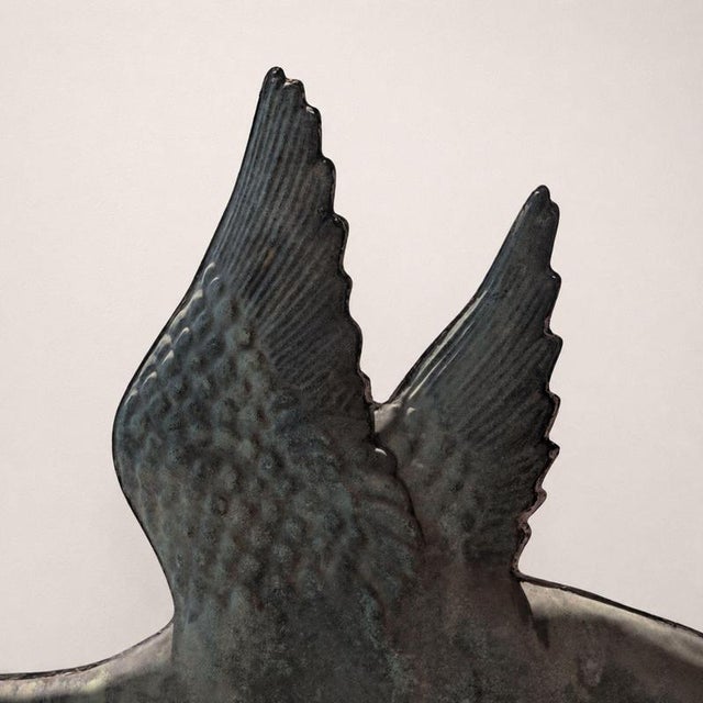 An elegant copper weathervane from the early 1900s, featuring a dramatic three-dimensional composition depicting a swan in...