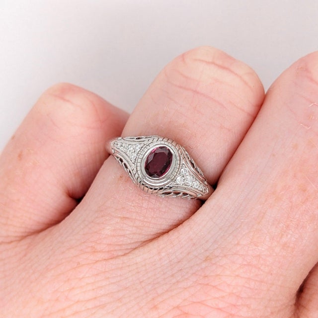 A red ruby takes center stage in a vivid red at the heart of this solid 14K white gold ring, flanked by twelve earth-mined...