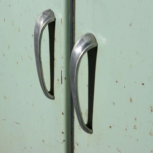 Industrial storage unit in lacquered metal with hinged doors and curved metal legs. This piece is attributed to the...