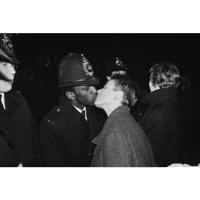 New Year Celebrations In Trafalgar Square A police officer kissing a young woman, who is wearing an overcoat, during the...
