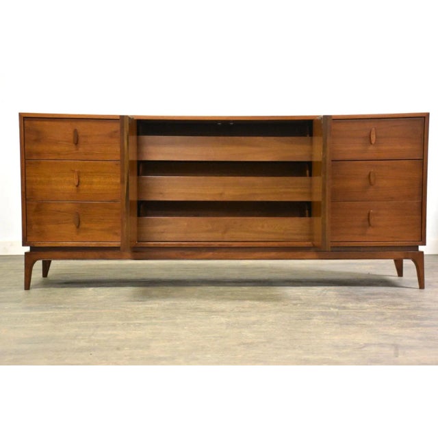 A mid century modern walnut dresser with sculpted details. Original finish is in excellent condition. 73.5” wide. 19”...