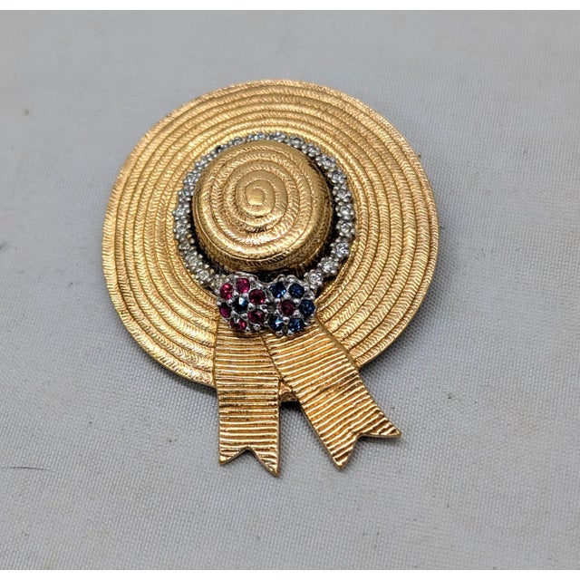 Goldtone sun bonnet with ribbon with small round faux-rubies and faux-sapphires making up flowers at the back with small...