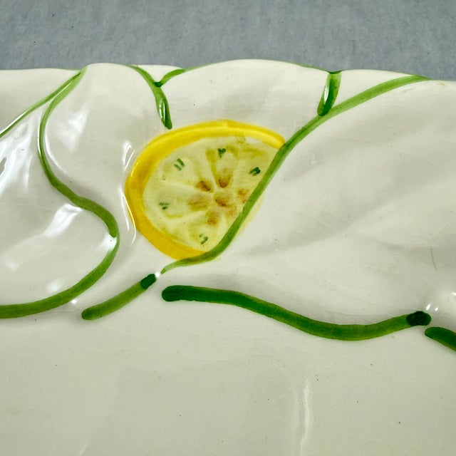 Made in Italy, a serving platter showing a border of green leaves and lemon slices, circa 1960-1970. An oval platter with...