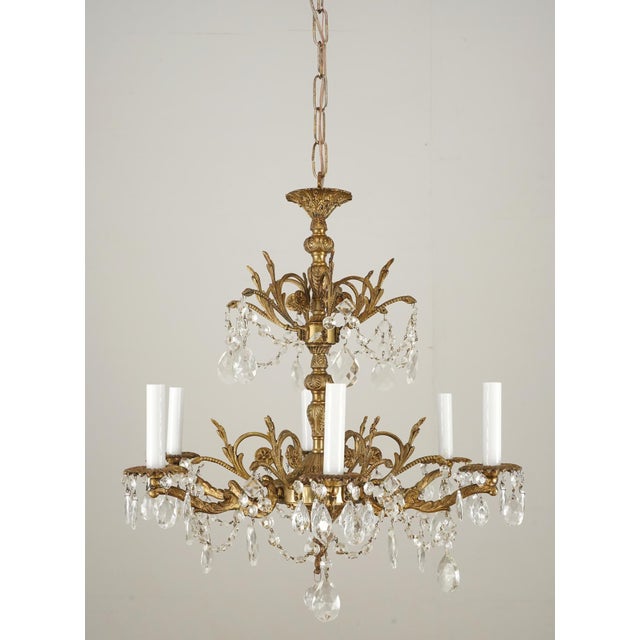 Spanish Rococo Revival crystal and brass chandelier with a gilt finish. There are ornate foliate motifs throughout the...