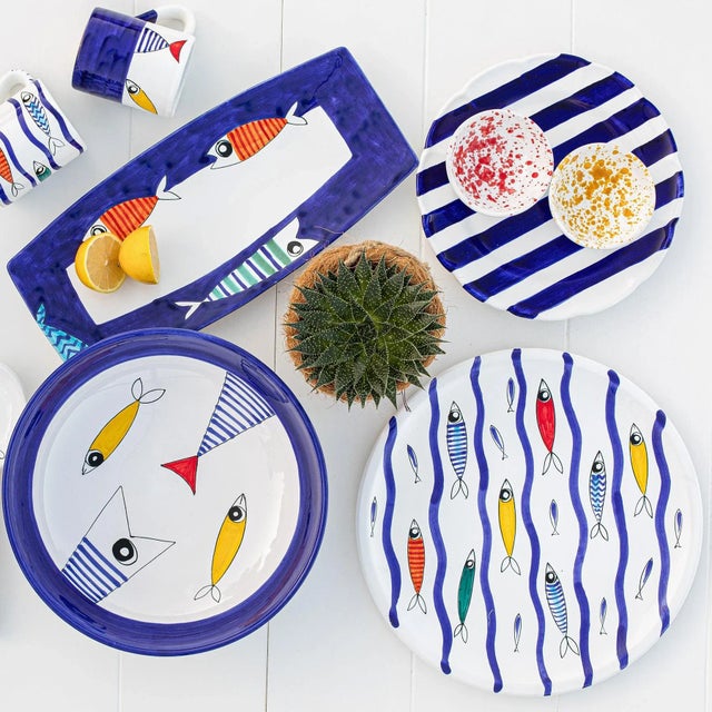 Pesce Pazzo (“Crazy Fish”) is a sophisticated, artistic take on seaside style. Handpainted solid, striped, and scaly fish...