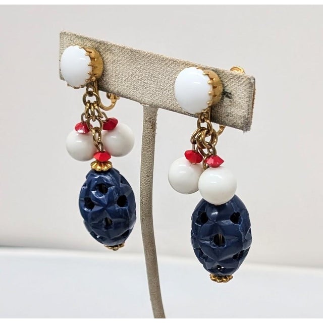 1960s goldtone white cabochon top with oblong "carved" faux=lapis bead drop and round white resin with small red spacer...