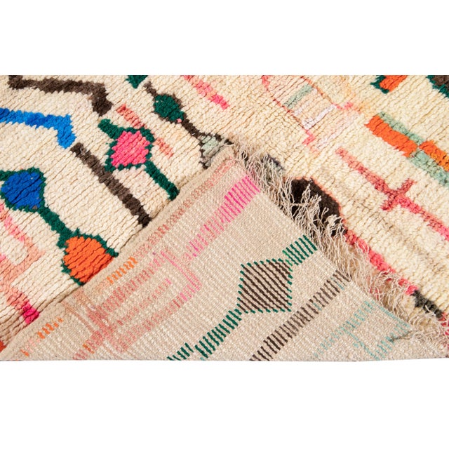 Beautiful Vintage Azilal Moroccan hand-knotted wool rug with the Ivory field. This Moroccan rug has a bright multi-color...