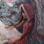 In "Story of Red," a figure clad in a vibrant red hood sits contemplatively against a textured landscape, blending...