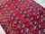 This classic Turkmen Bokhara rug showcases an allover field of repeating octagonal "gul" medallions in deep burgundy,...
