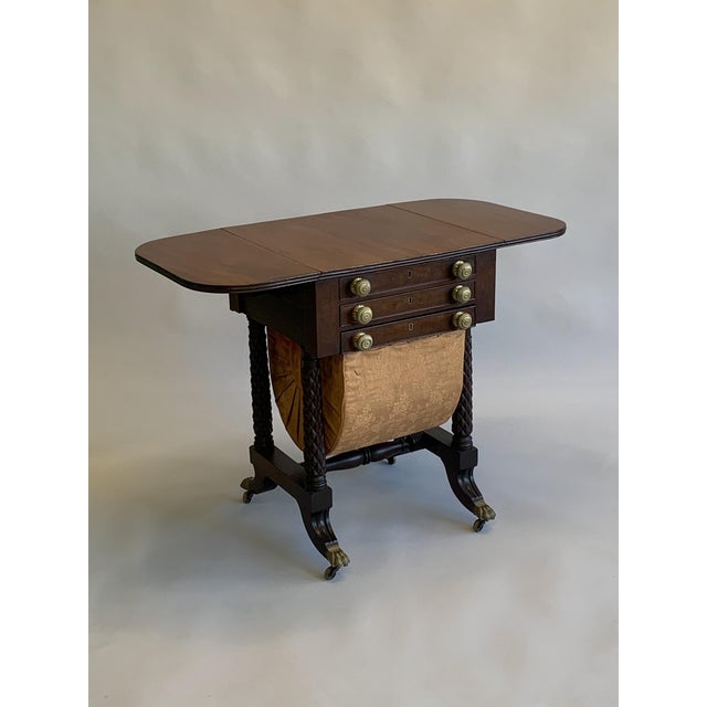 Antique Early American drop leaf work table. Solid mahogany with brass pulls and capped feet and casters. The table...