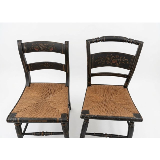 A charming set of two vintage hand‑painted folk art rush‑seat chairs, dating to the Mid‑20th Century (1950s–1970s). Each...