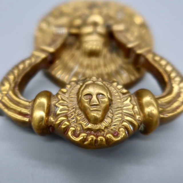 A substantial vintage door knocker cast in solid brass, featuring a detailed lion head with a full mane set against a...