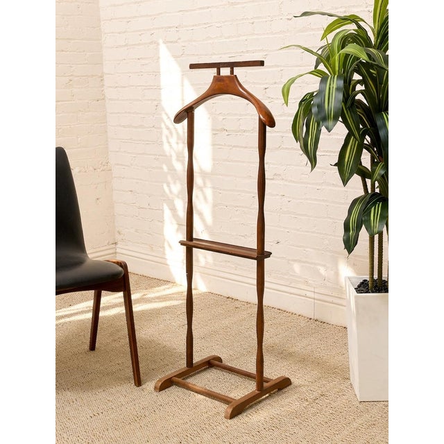 A handsome vintage gentleman’s valet stand in warm walnut, designed to keep a jacket, trousers, tie, and everyday...