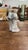 An elegant vintage porcelain figurine depicting a newlywed couple in classic Lladró-inspired soft pastel tones. The groom...