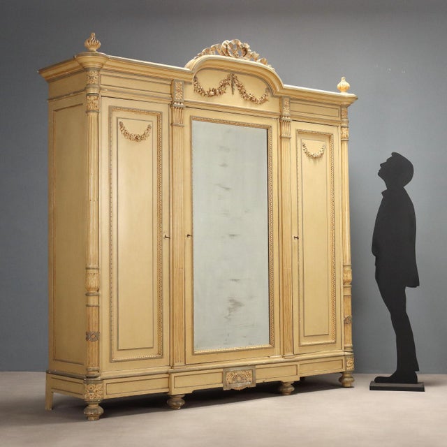 Neoclassical-style wardrobe in lacquered cherry and walnut. Central mirrored door and side panels with carved festoons and...