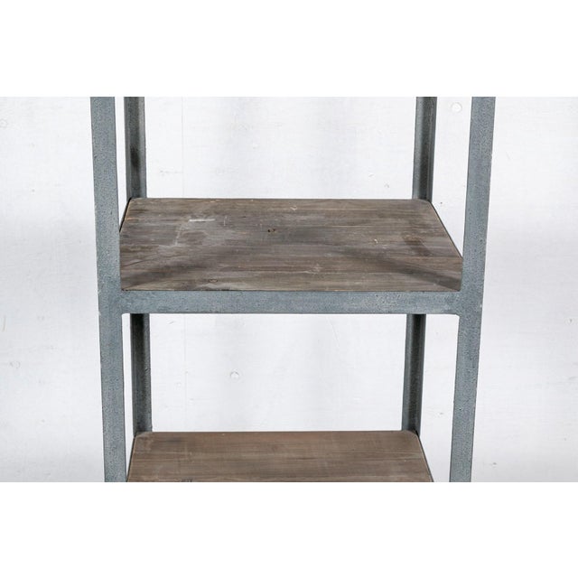 A tall, narrow industrial-style etagere with a durable gray painted metal frame and six, reclaimed weathered wood plank...