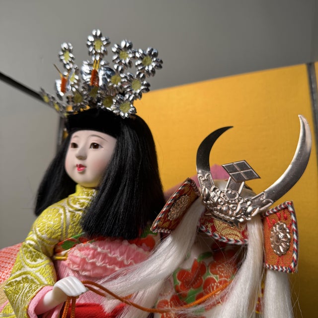 This refined Japanese doll is presented in a glass display case with a black lacquered wooden frame. The case opens from...