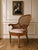 A beautiful antique Victorian cane back armchair with wonderfully sculptural carved wood details, curled arms, a rounded...