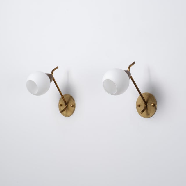 Pair of italian wall sconces dating from the 1950s, characterized by a light and sculptural brass structure combined with...